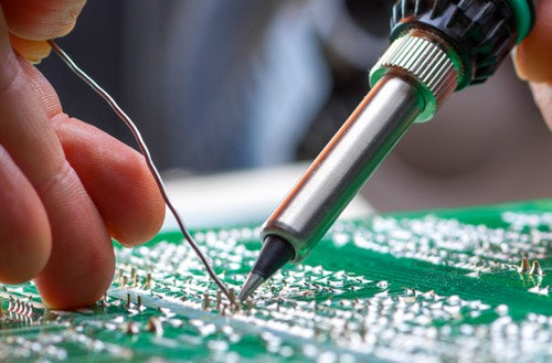 Hand soldering a wire onto a circuit board